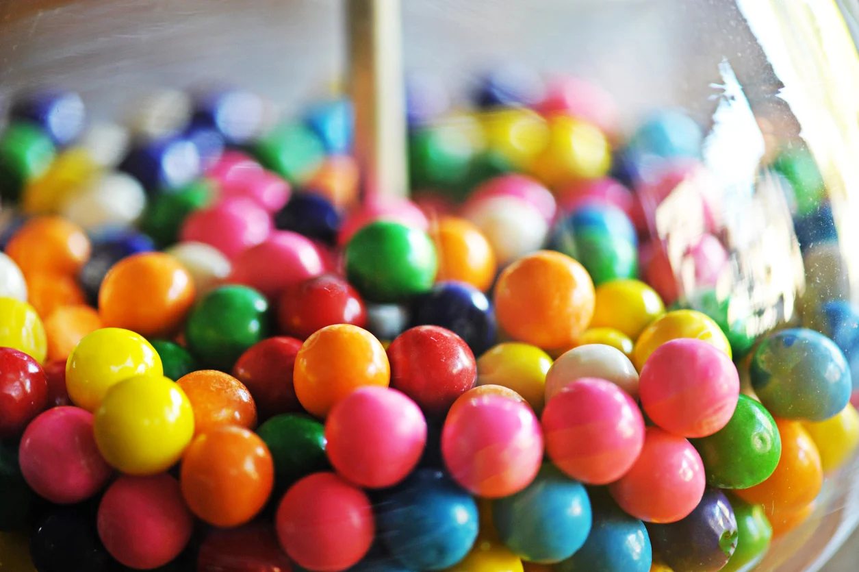 Multi colored gum balls in a gum ball machine.