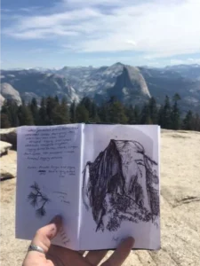 2017 participant Erika Mitkus, a 2016 Knowles Teaching Fellow, journaling at the peak of Sentinel Dome, looking out over Yosemite Valley and Half Dome.Photo credit: Erika Mitkus.